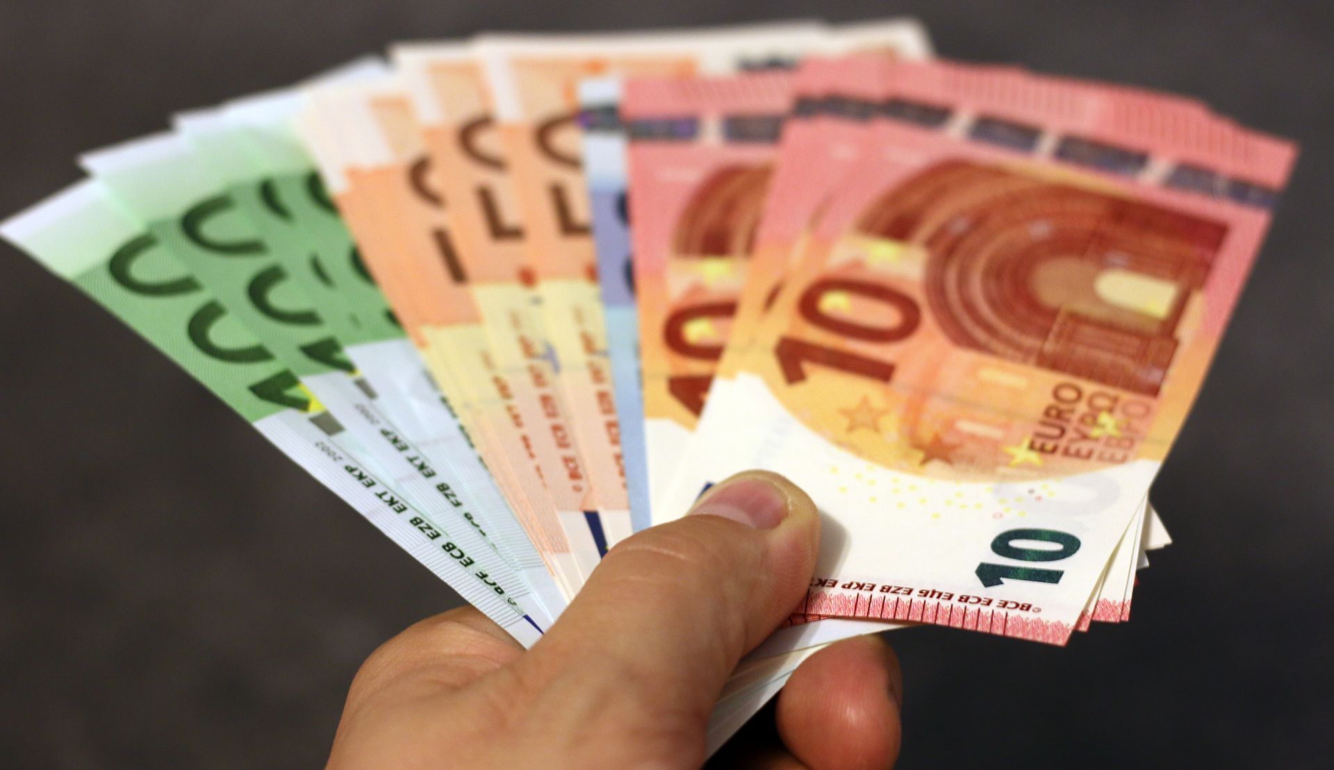 Éventail de billets en euros tenus à la main, symbole des dividendes